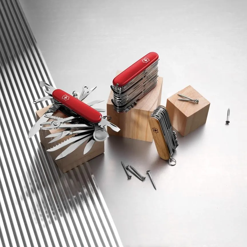 Three Victorinox Forester multitools are displayed on wooden blocks, with one unit fully fanned out to show its tools and the other two folded.